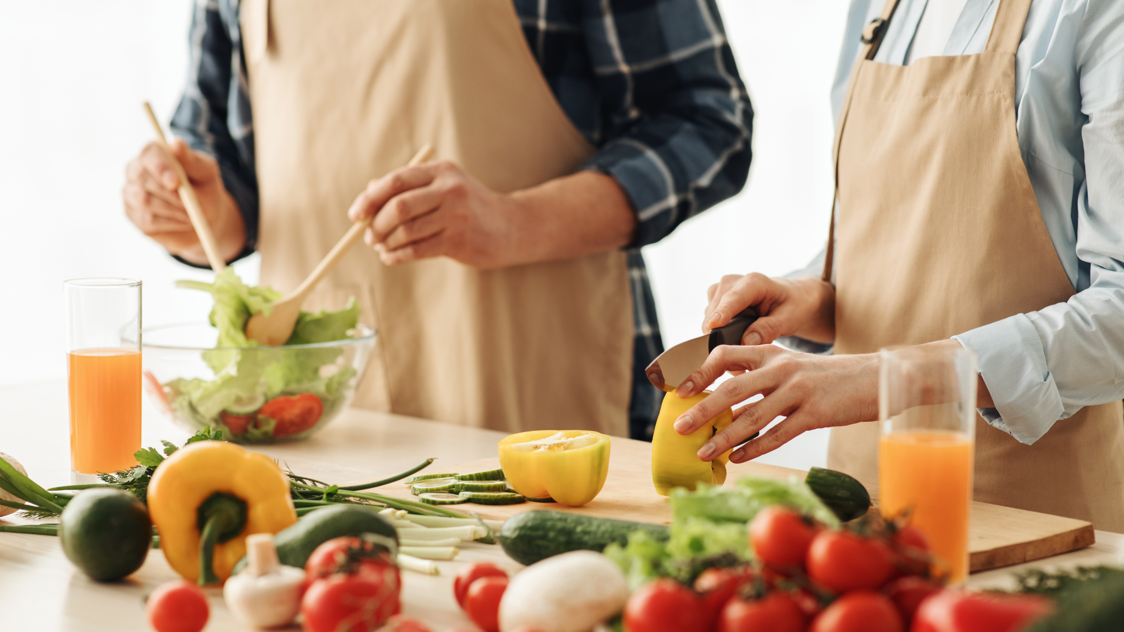 Senioren sind zusammen aktiv mit dem caera Notrufarmband. Sie kochen und achten auf gesunde Ernährung.